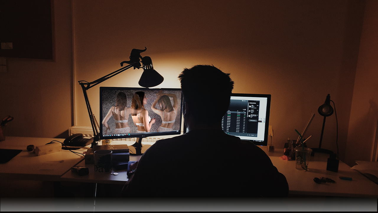 Mann sitzt nachts am PC und konsumiert Pornos